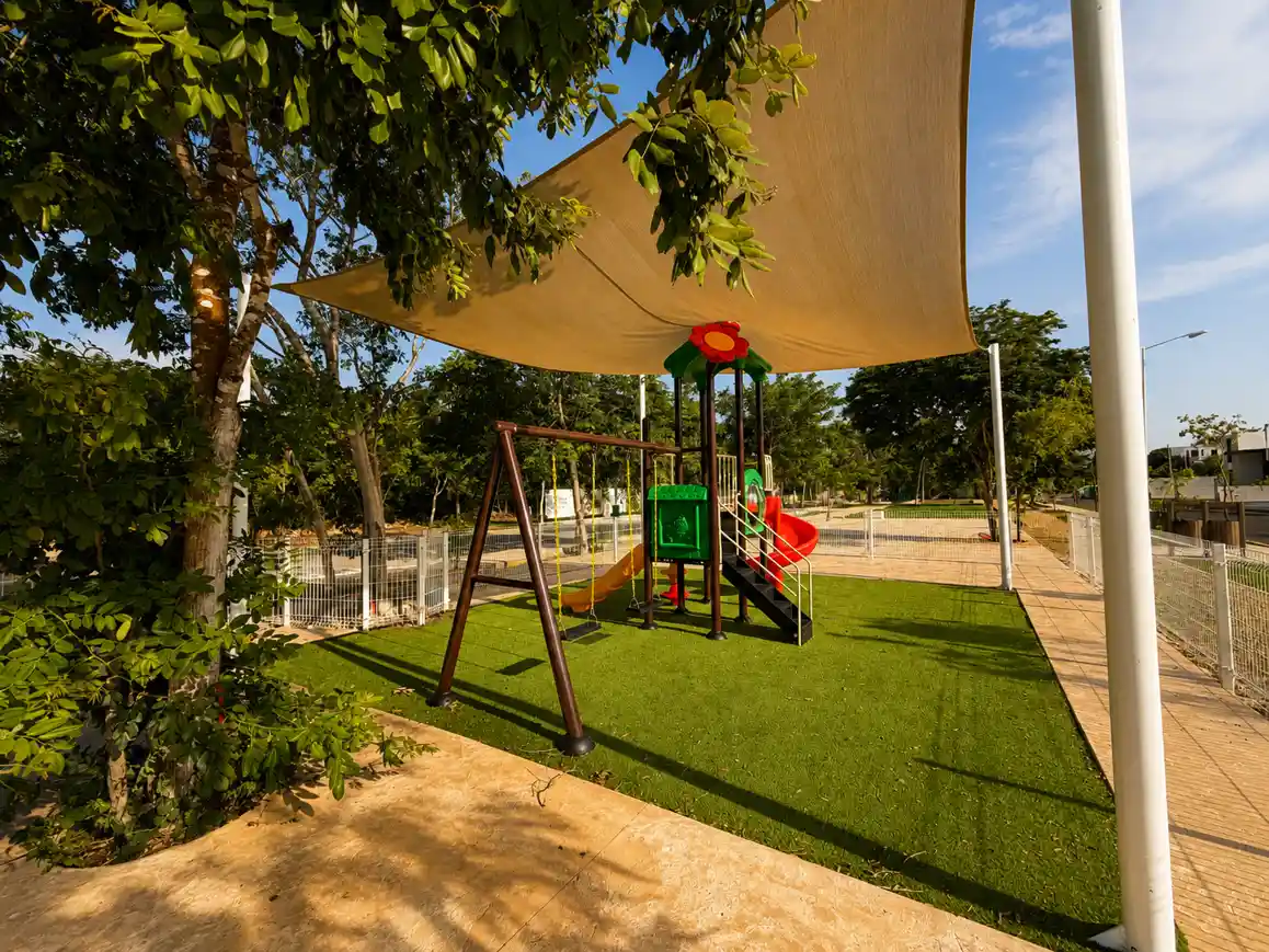 Juegos infantiles con columpios bajo velaria en el Parque Central de Bosques de Cholul